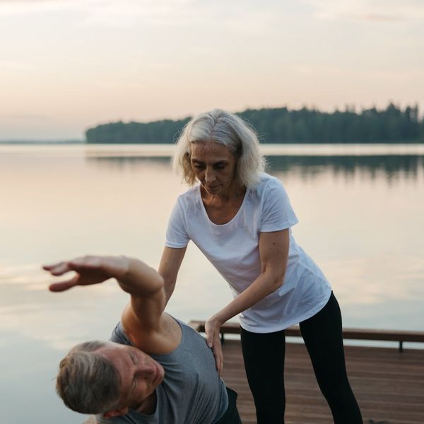 Person stretching gracefully outdoors during a beautiful sunrise.